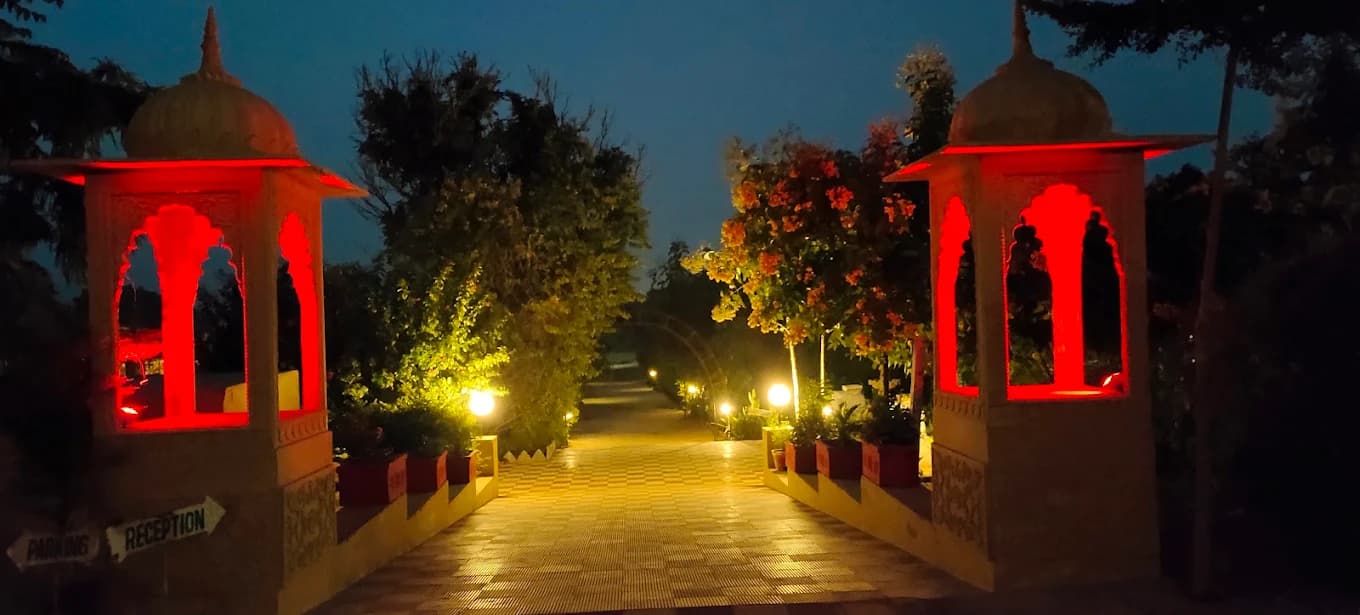 Lit pathway between chhatri gate pillars at night